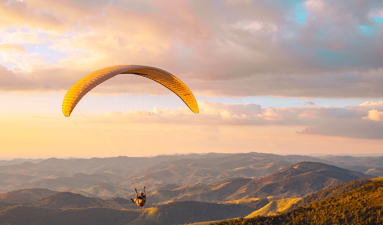 Essa imagem retrata varios atletas praticando voo livre nos ceus de Raul Soares