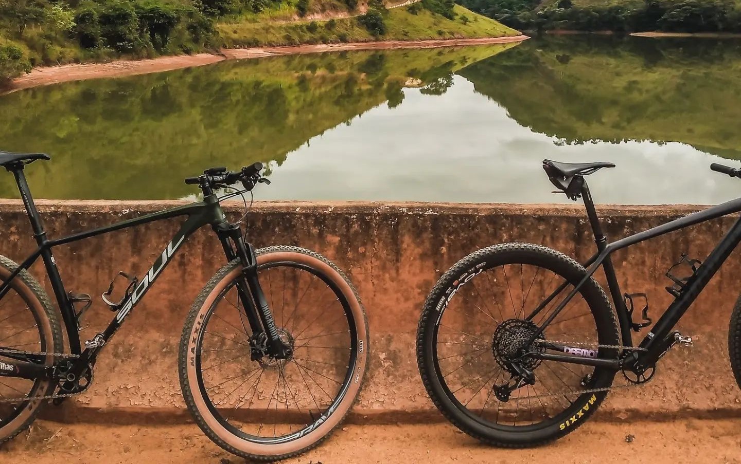 Essa imagem retrata a represa do emboque, uma vista cênica de um reservatório azul calmo cercado por colinas verdes sob um céu claro